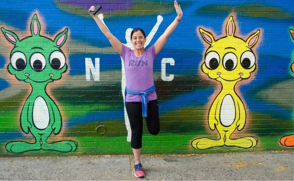 NYC Marathon runner smiling with hands up NYC Marathon Guide