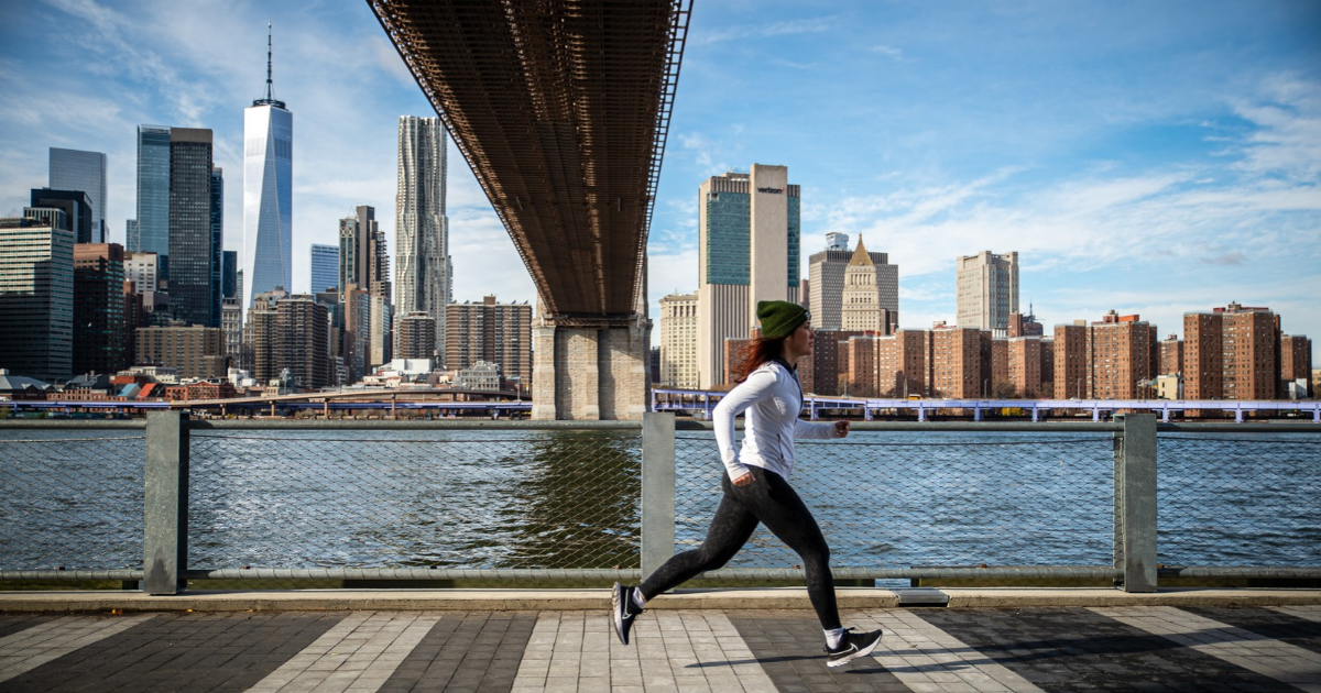 woman cold weather running under Brooklyn Bridge in NYC winter