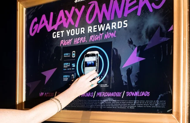 Fans hold Samsung Galaxy phones to NFC-enabled signage to participate in the Samsung Galaxy Owner's Experience at AEG venues.