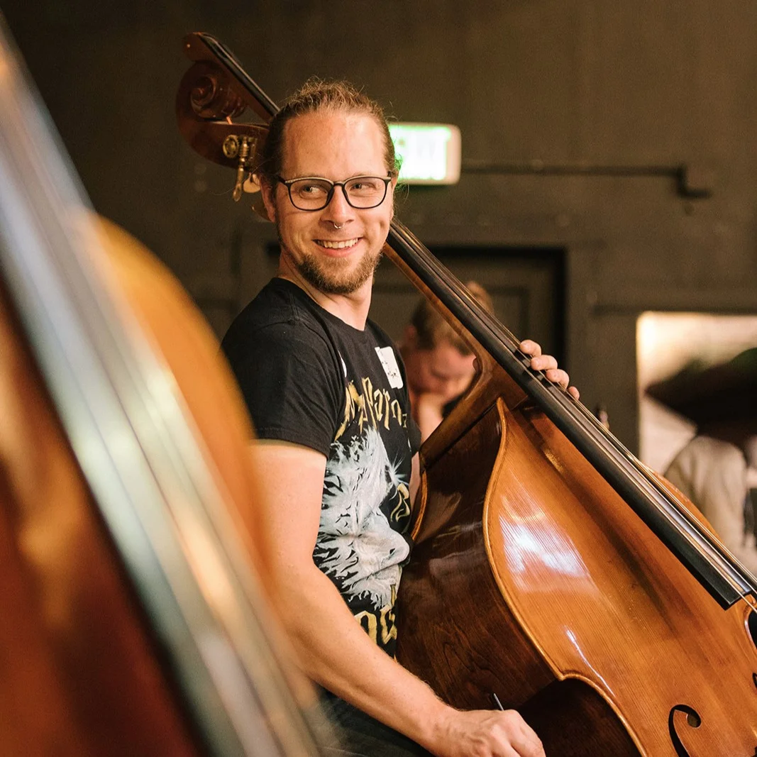 BASSES: Travis Kindred Travis is your friendly resident bass player! He's happy to say hello, give you a hug, hand you a drink you might like, and generally do whatever he can to help enable you to have an awesome time. Travis has been with AOC from the very beginning (the first session was held in his living room!). You can also find him playing with several bands in the Bay Area and serving as the education designer for Ubisoft. He's also a huge fan of D&D, Gunpla models, obscure video games and movies, and has an unreasonable love for Godzilla.
