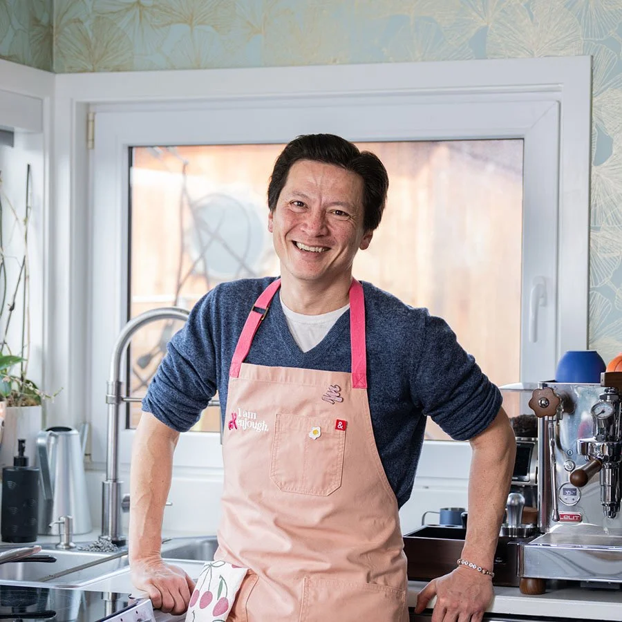 Kenji Lopez-Alt smiling in a pink apron