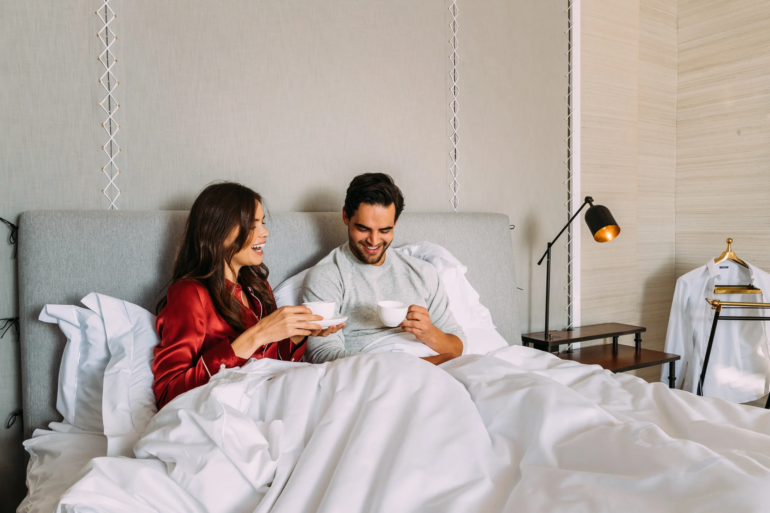 A couple having coffee in bed in the Presidential Lodge at Delaire Graff Lodges & Spa