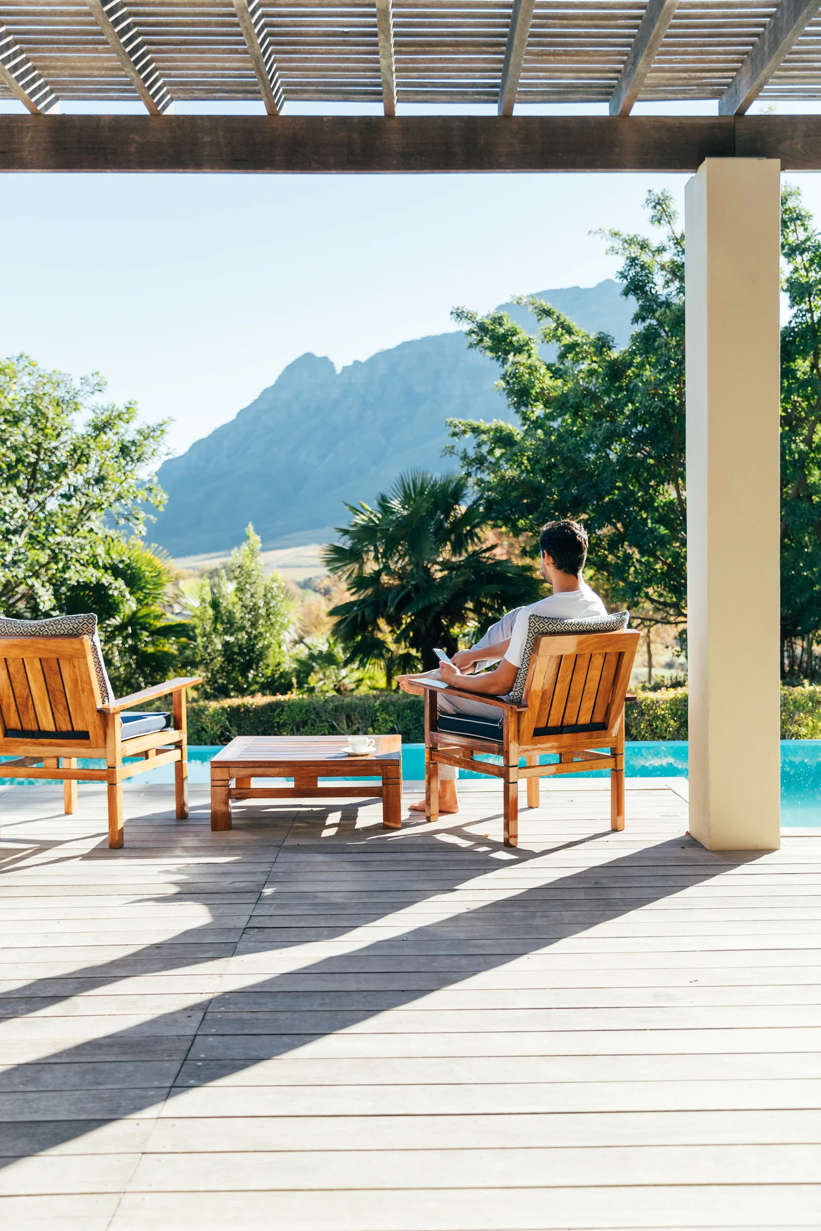A man sitting on the private deck of the Presidential Lodge enjoying the views across the Stellenbosch Valley from Delaire Graff Lodges & Spa