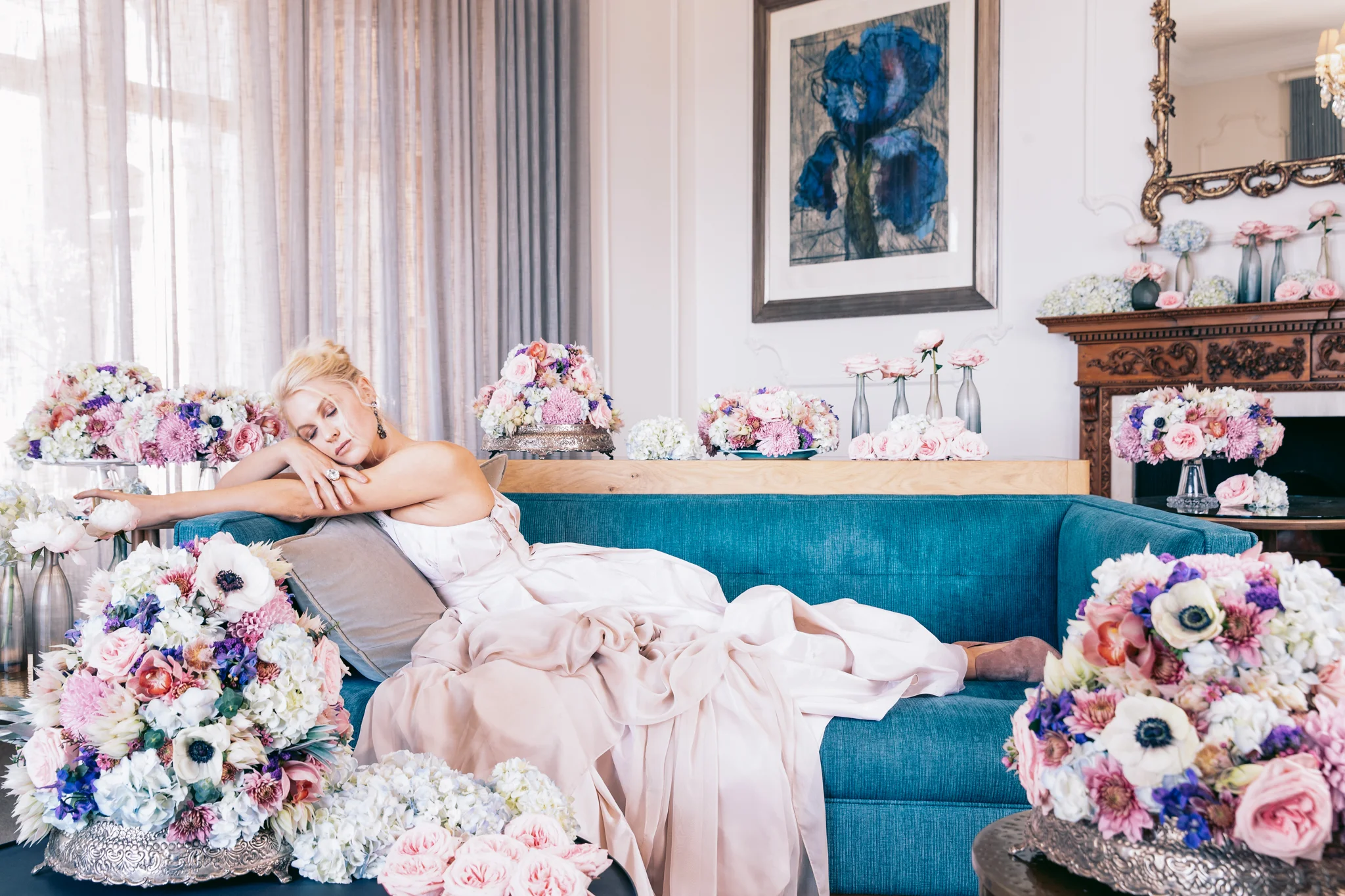 Girl lying on couch in pale pink KluK CGDT dress with champagne in hand surrounded by flowers at Ellerman House