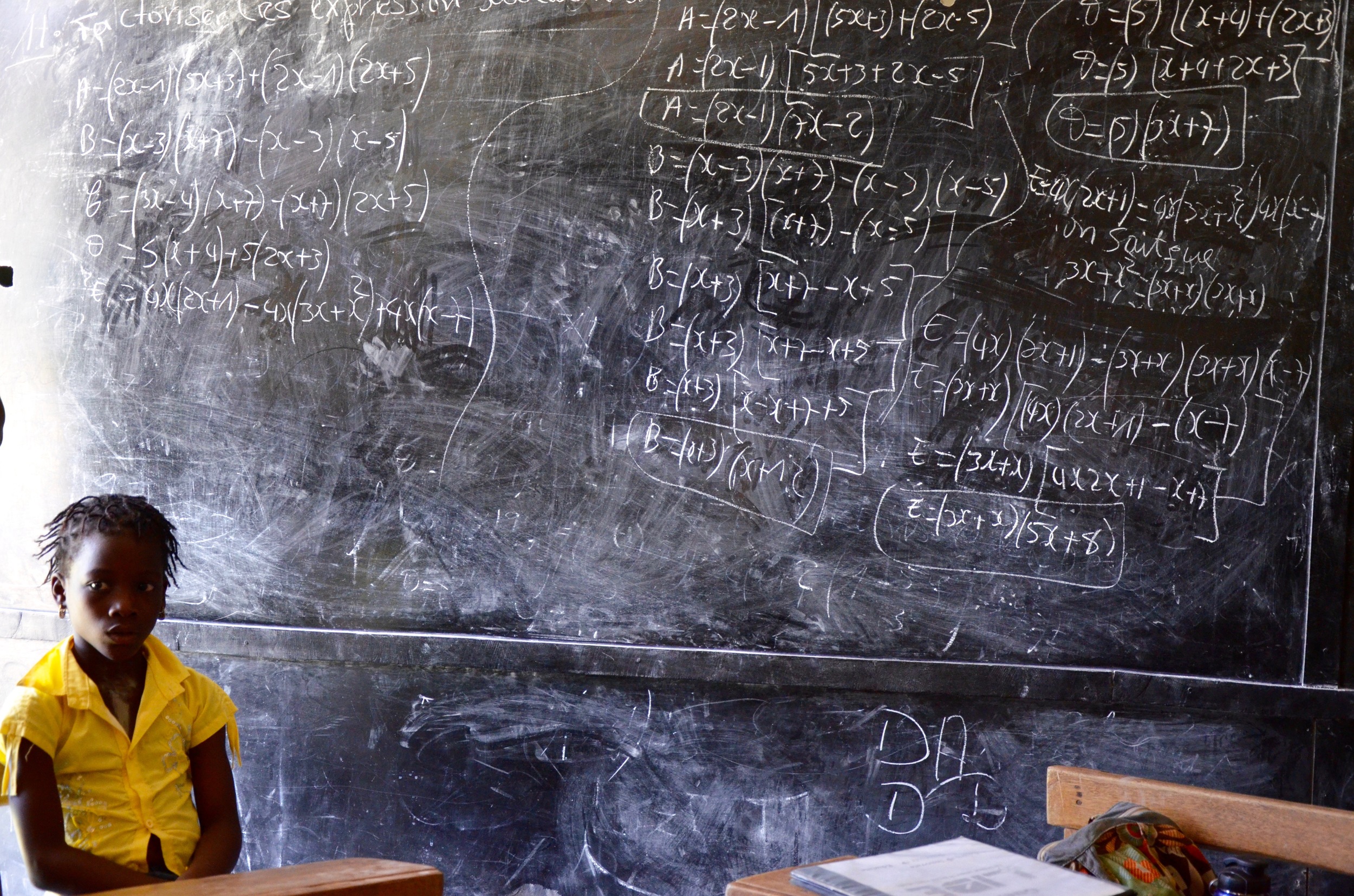 Guerot- Using the local school's classroom on a Saturday, a child sits next to a classic chalkboard ladened with algebra.