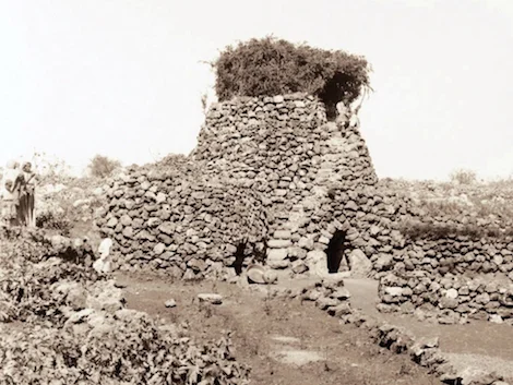 An agricultural watchtower photographed in the last century (ca. 1900-1920). Note the stair on the near side with a seated man near the top, the brush covered turret, and the arched doors leading into enclosed rooms beneath. Image from here .