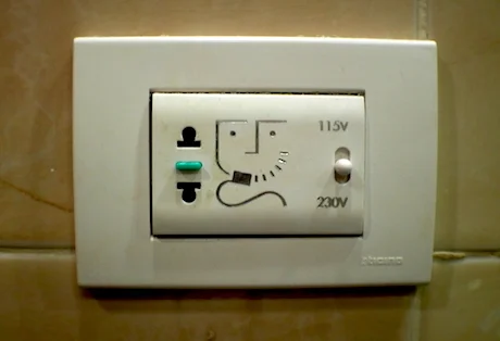 Some hotels have these in the bathroom. Notice that you can flip the switch to shift from 115 V to 230 V. Notice also the plug (a 2 holer) that can take blades or pegs. Finally, notice the little man getting a shave. Nice, eh? Not every hotel will have these, though.