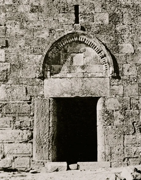 The way in. Image from here . Note how the doorframe is not symmetrical but is pieced together by recycled architectural fragments. An archer’s slit (loophole) is visible above a relieving arch that protrudes forward as a hood mould. The hood mould is ornately decorated (“gadrooned”) by radiating lines. Compare it with better executed entryway at the Church of the Holy Sepulcher in Jerusalem here .