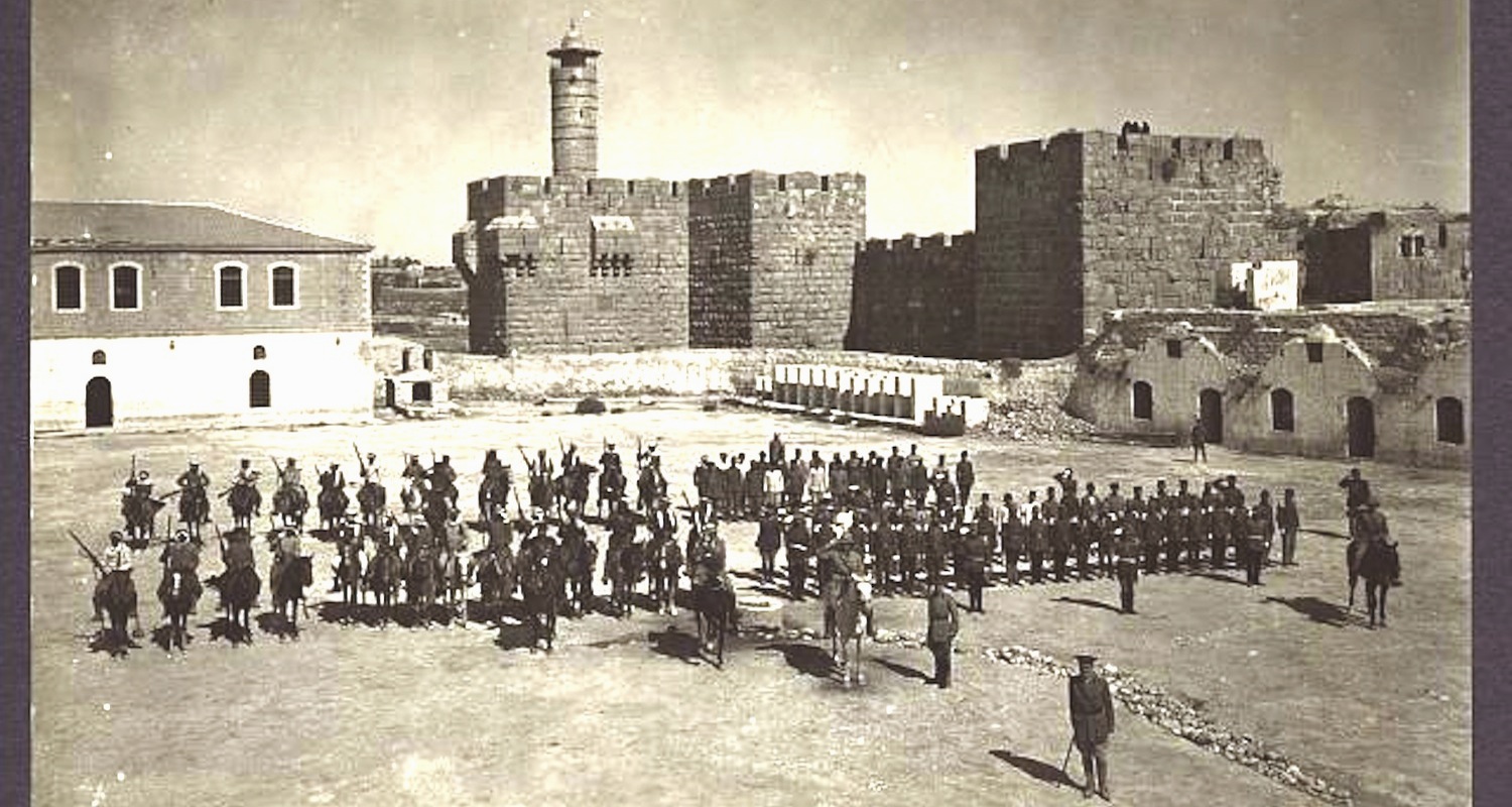 This photograph shows “Barracks Square” in 1918. Compare the facades of the perimeter buildings on right to the view of the modern police compound above. Image from here .