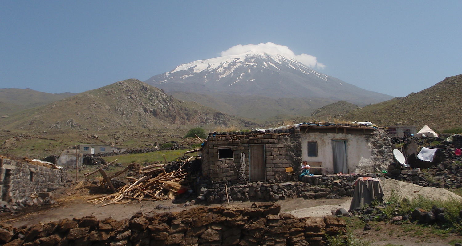 A house in Çevirme. The snowy peak of Agri Dagi, traditional Mt Ararat, rises in the distance. Dung-cakes are arranged on a wall in the foreground.