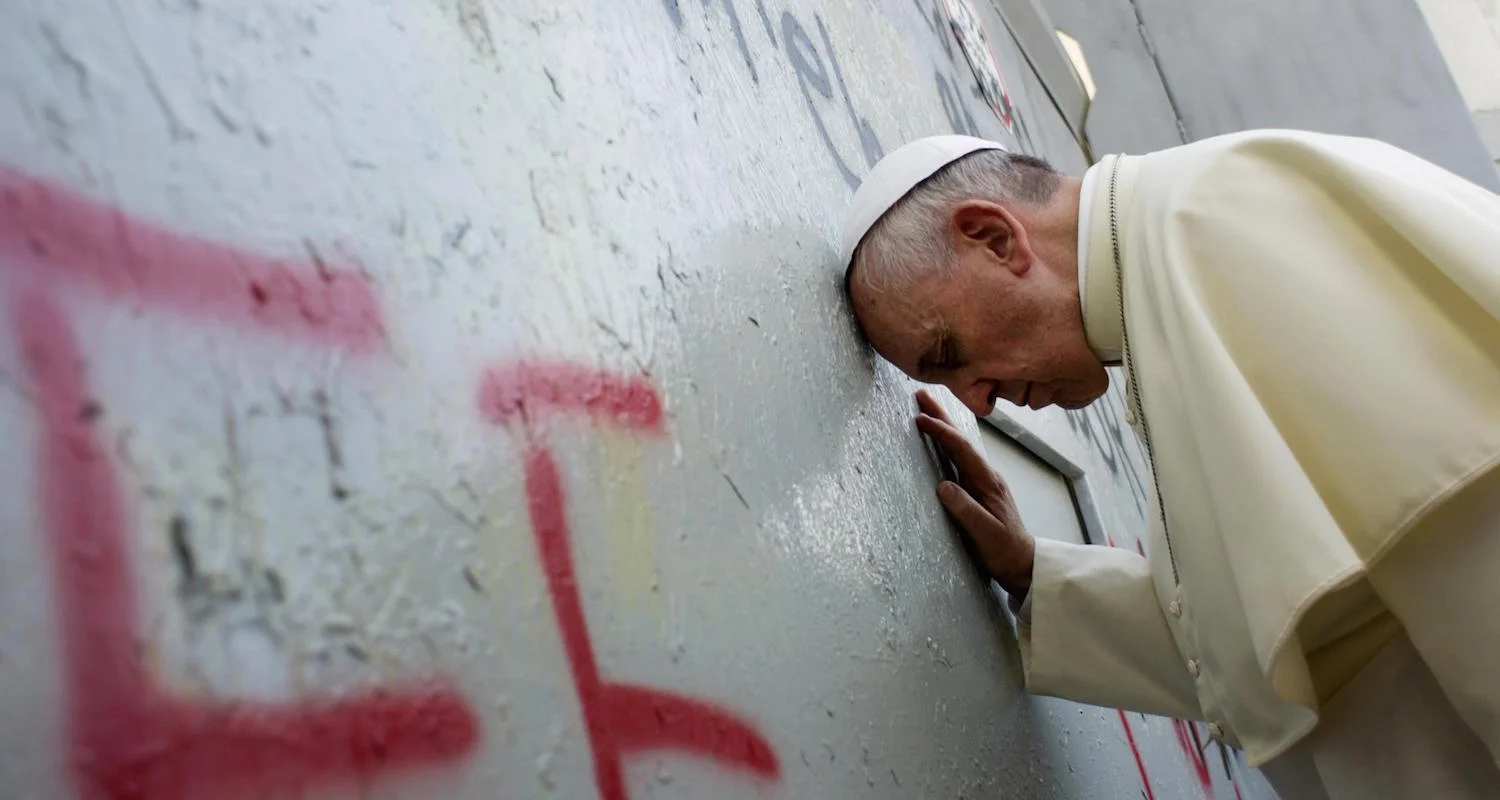 Pope Francis prays at the wall. The graffiti under his head in red letters reads “Free Palestine.” Image from here .