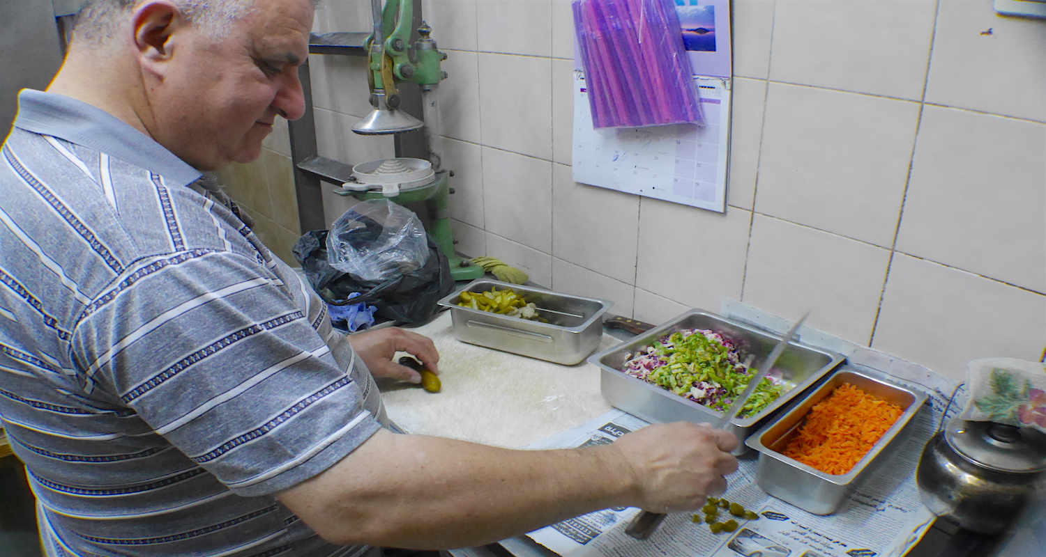 Sameer prepares his sandwich fixins.’