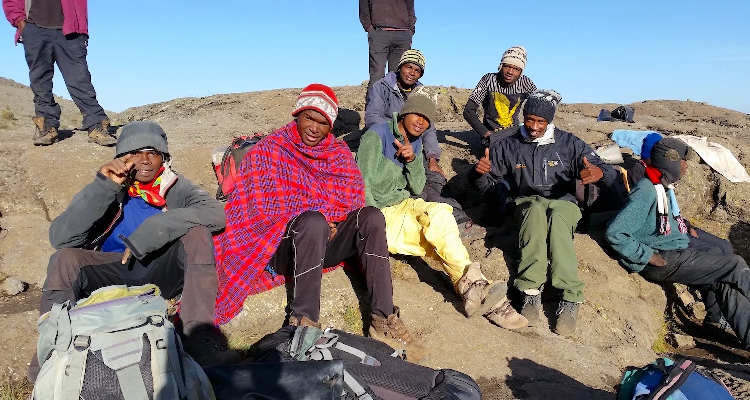 Our porters warm themselves in the sun. My man Dennis is there in the green coat and yellow pants.
