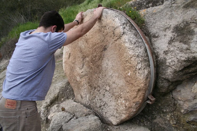 One of our Bible Land Explorer poses for scale. The steel band on this rolling stone should help prevent looters from taking it.