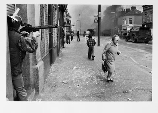 NORTHERN IRELAND. Belfast. Catholic West Belfast. Falls Road. Hijacked vehicle burns in the background marking the anniversary of the British Policy of internment without trial. 1978.