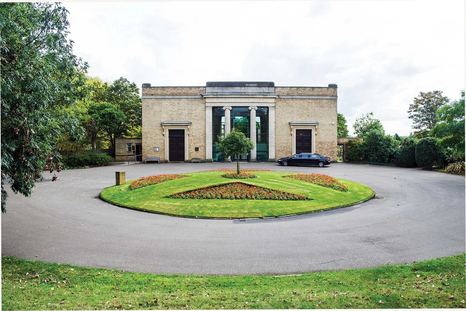 The pale brick entrance and circular flowerbed at West London Crematorium
