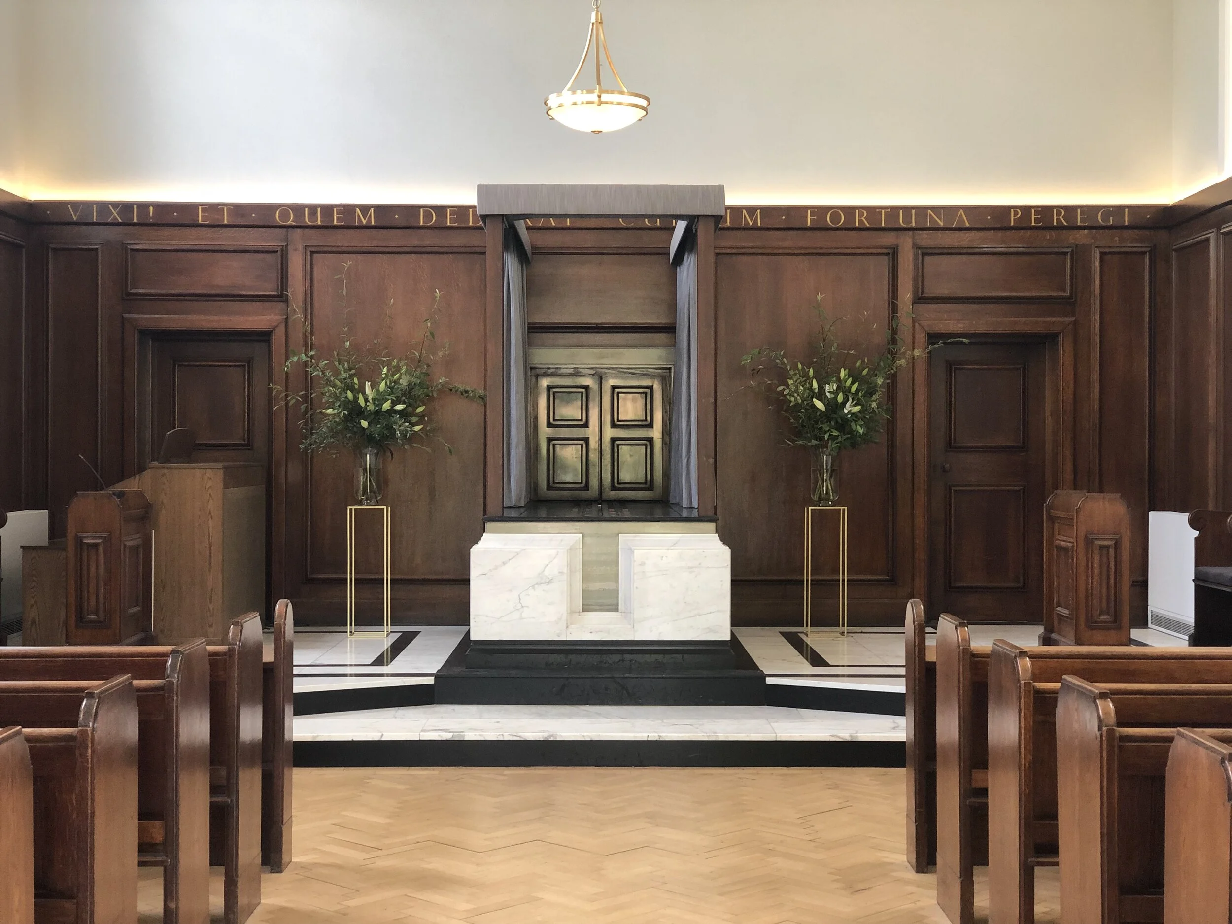 Traditional oak pews, wood panelling and the marble catafalque in the East Chapel at West London Crematorium
