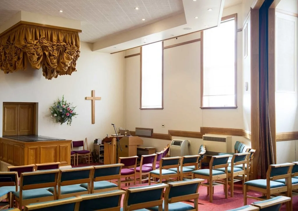 Light oak seating and the curtained catafalque in the West Chapel at West London Crematorium