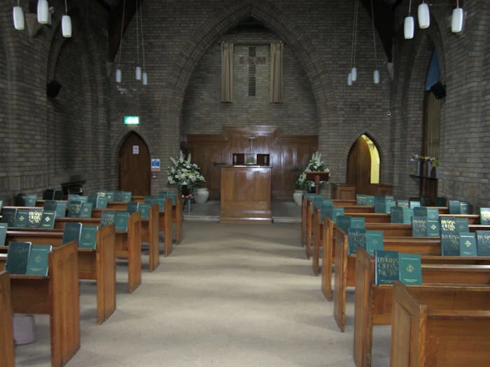 The West Chapel at Croydon Crematorium with vaulted brick ceiling and rows of wooden pews