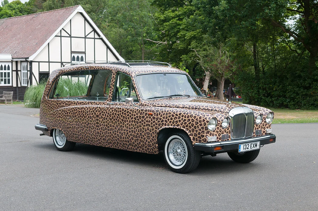 Full view of the leopard-print vintage Daimler hearse parked outside