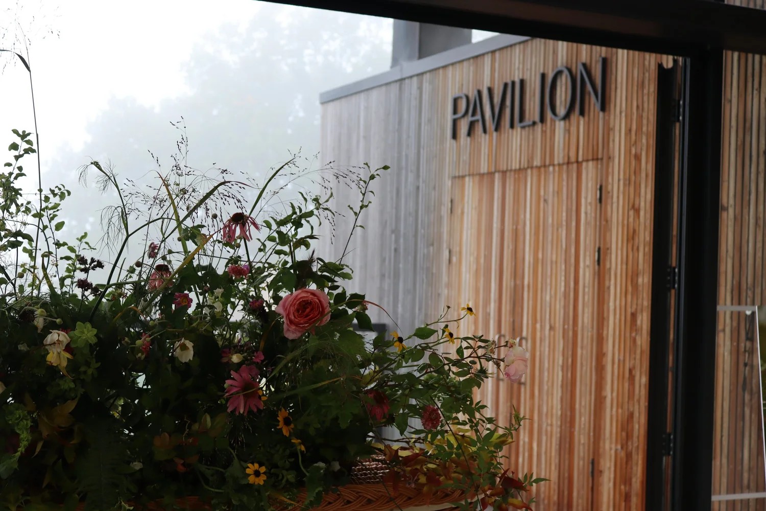 Flowers beside the timber wall marked Pavilion inside the Horniman Museum venue