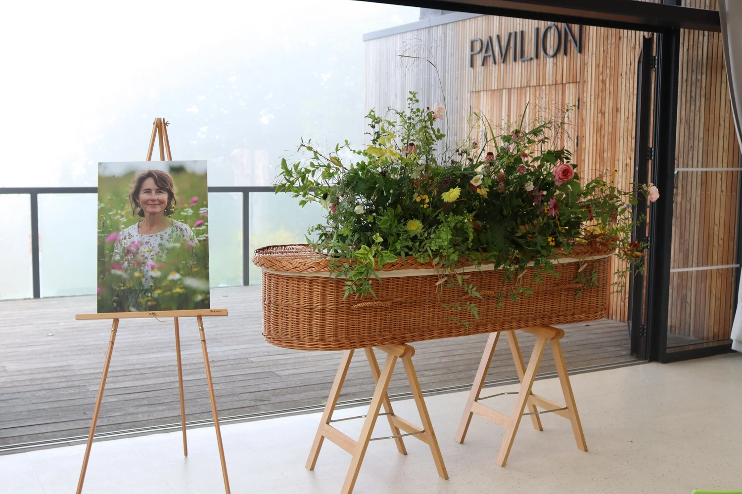 A wicker coffin decorated with flowers beside a portrait inside the Horniman Pavilion