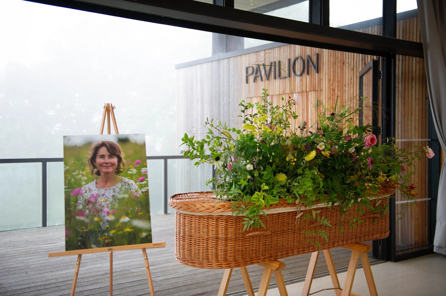 A wicker coffin with flowers beside a portrait in the Horniman Pavilion