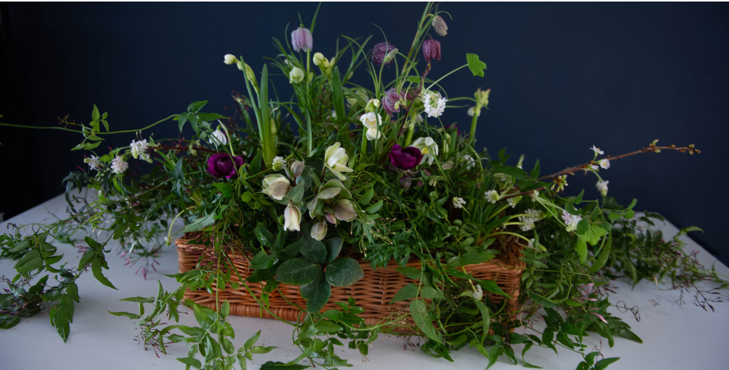 Planted spring flowers and greenery in a shallow woven basket