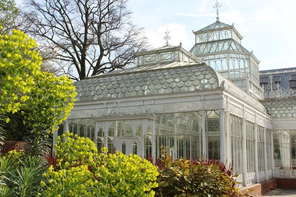 The ornate glass and iron exterior of the Horniman Conservatory amid the gardens