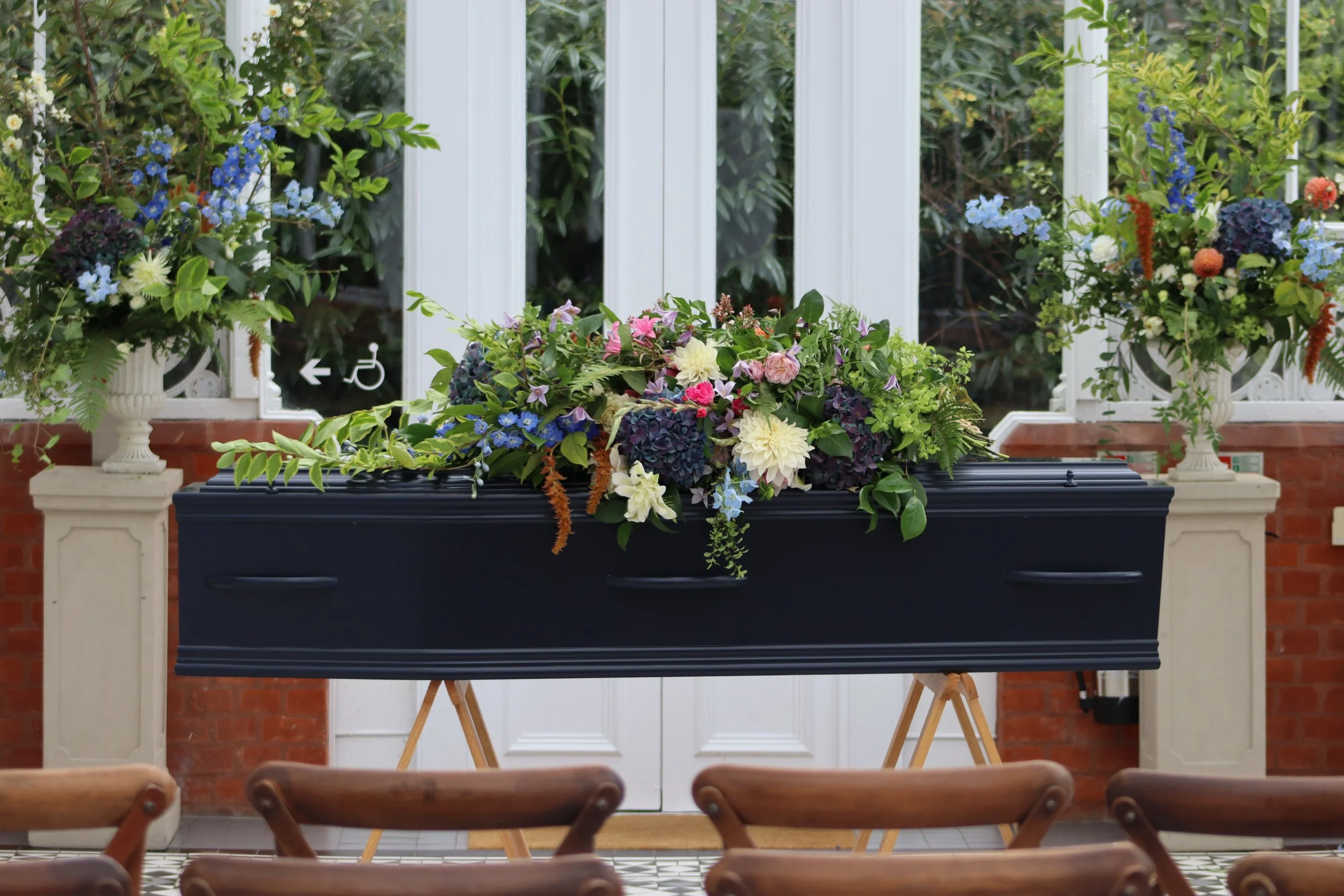 Dark blue coffin with a colourful arrangement of flowers at a funeral arranged by Poetic Endings
