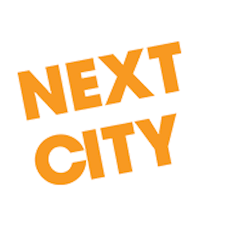 The words 'NEXT CITY' in bold orange letters, tilted at an angle.