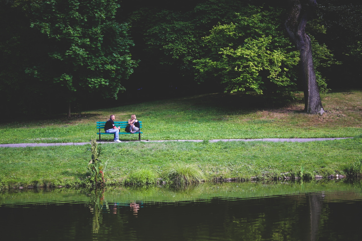 Two people talking on a bench outside