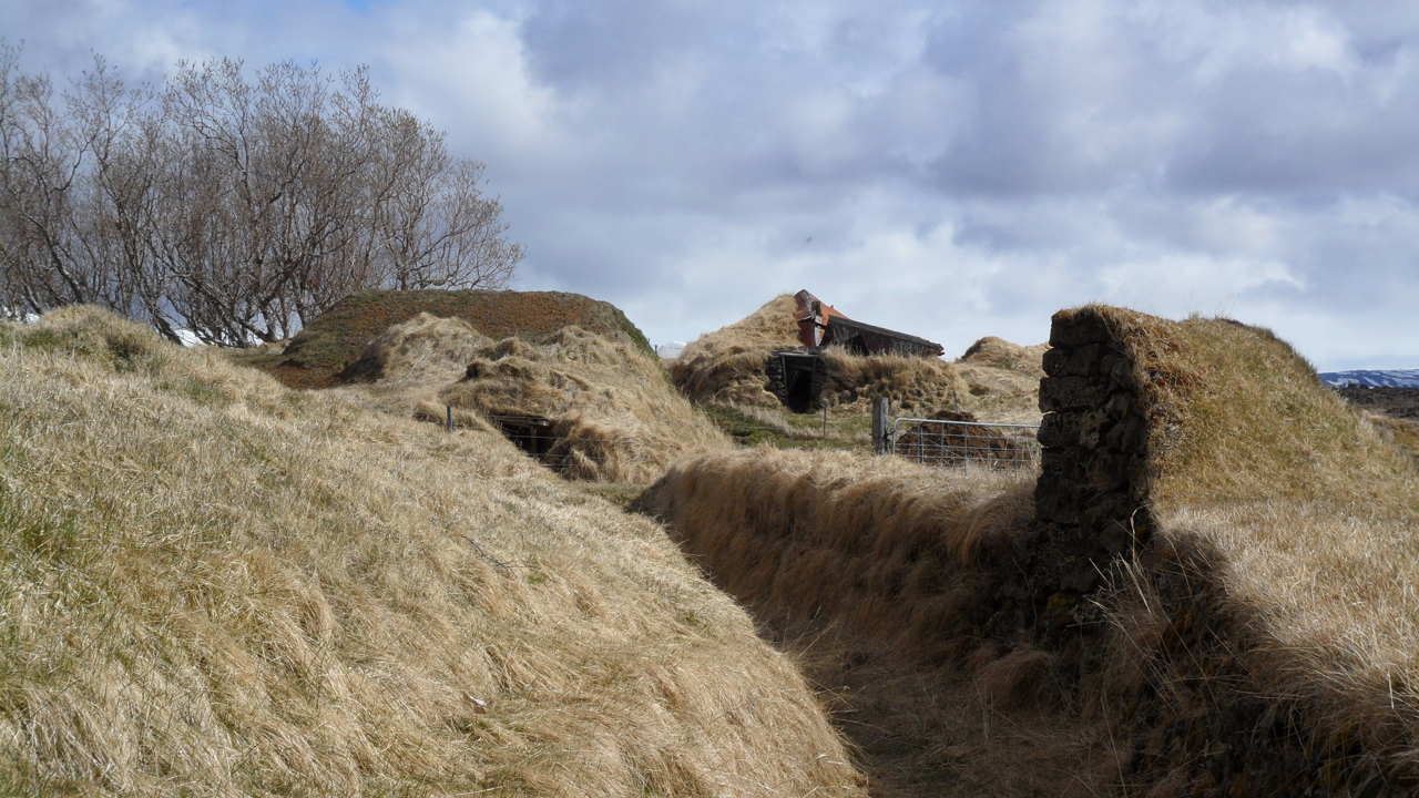 Crumbling sod buildings outside the fenced Keldur site.