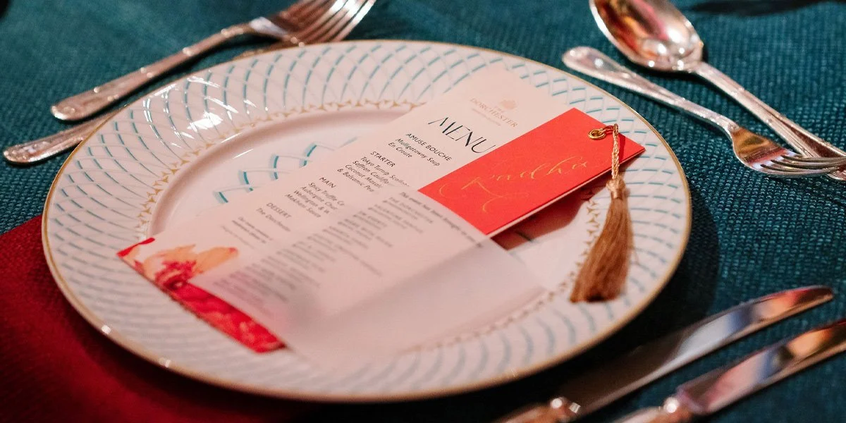 Elegant menu design for Dorchester Collection with vibrant pink name tag, gold tassel and overlay