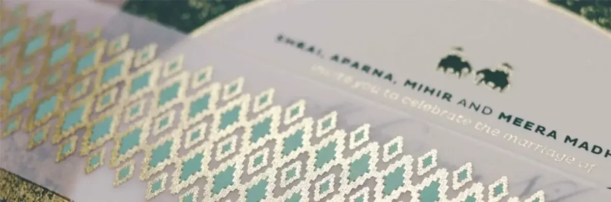 Close up of gold foil pattern belly band wrapped around dark green cultural style invite