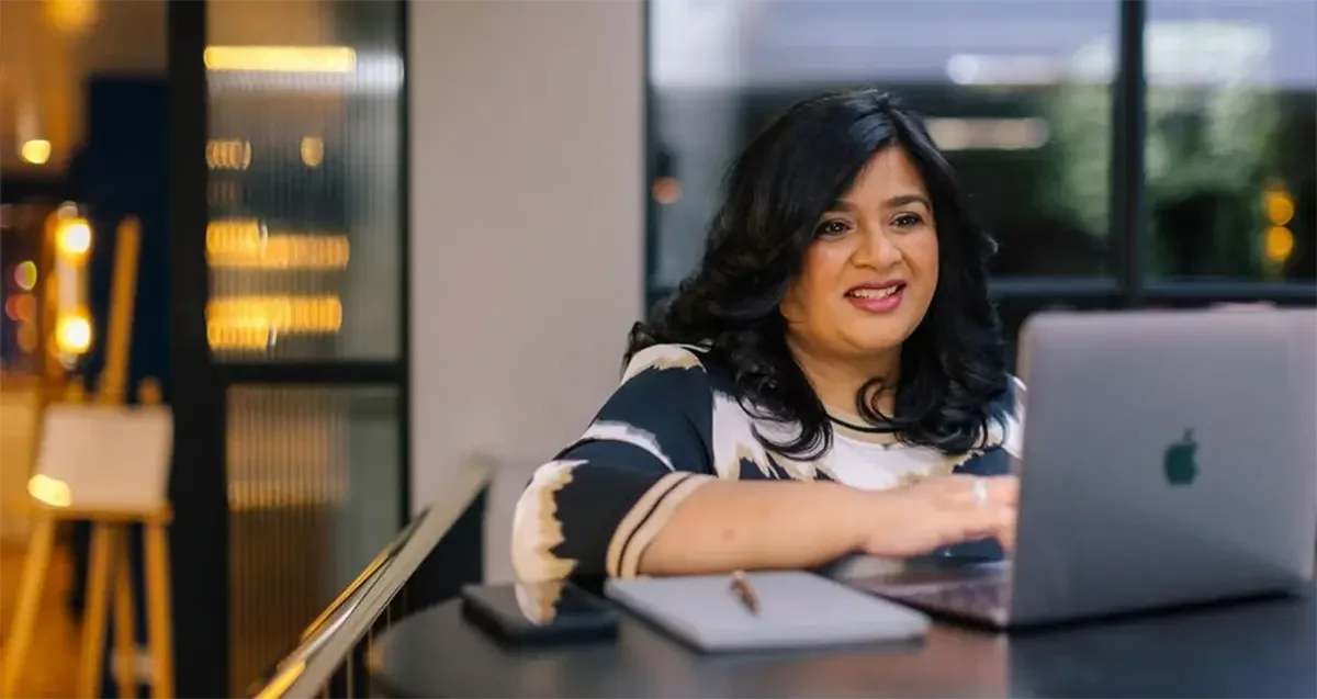 Vaishali Shah, founder of Ananya Cards, smiling while working at laptop
