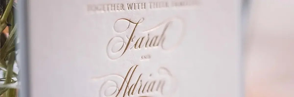 Close up of gold foil script font of couples names on white invitation