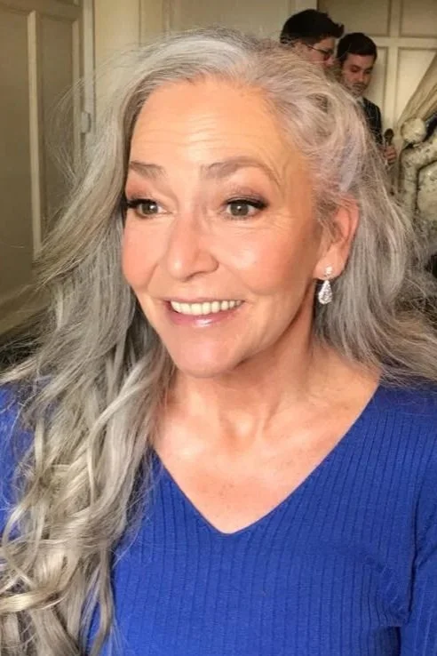 A smiling woman in a wedding dress holding a bouquet of flowers.