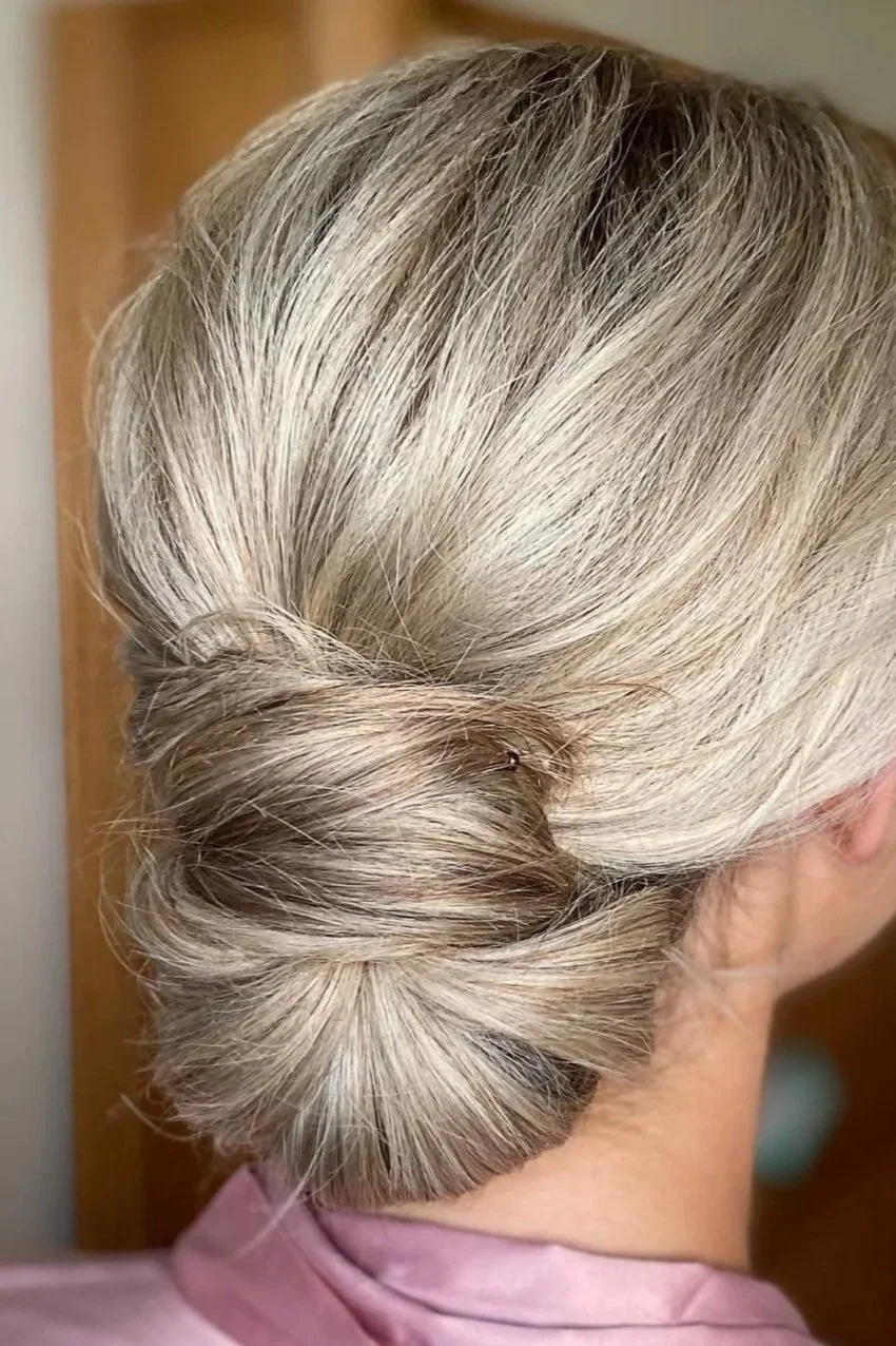 Black and white photo of a woman in a wedding dress with buttons on the back, wearing a veil, standing indoors.