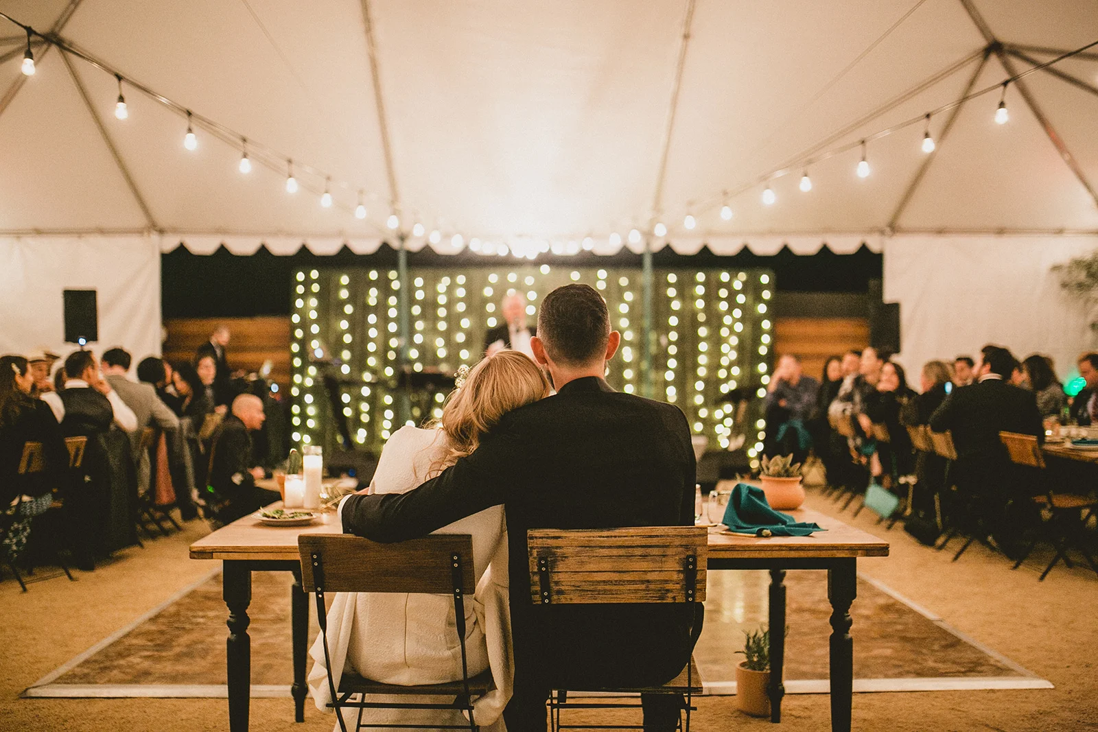 Bride and groom at a sweetheart table under a tent at their Lautner Compound Wedding in Palm Desert.