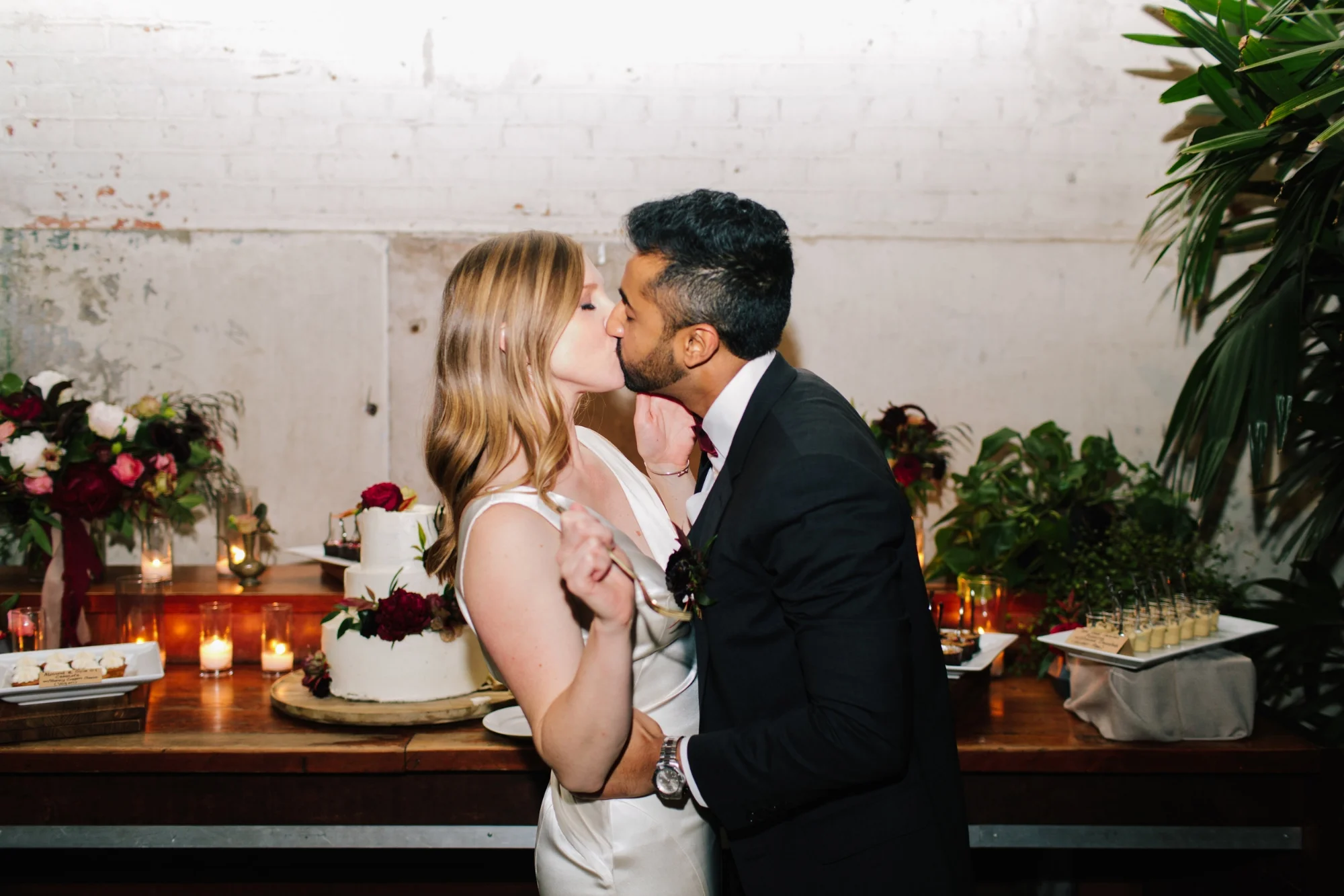Cake Cutting Kiss bride in a white gown with her Sri Lankan Groom in a charcoal Dolce Gabbana Suit, Millwick Wedding, Dessert Bar
