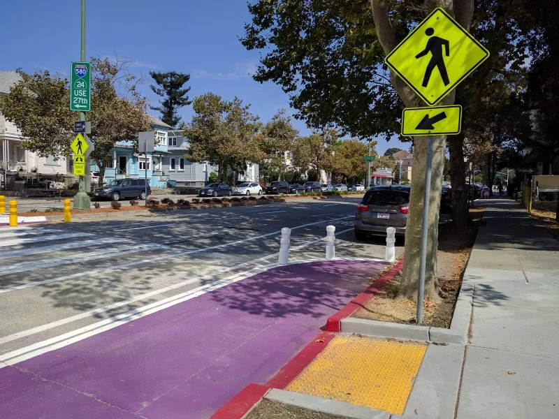 Mid-crossing bulbout, wider croswalk, and blastic bollards on the otherwise dreary and dangerous Harrison St in Oakland