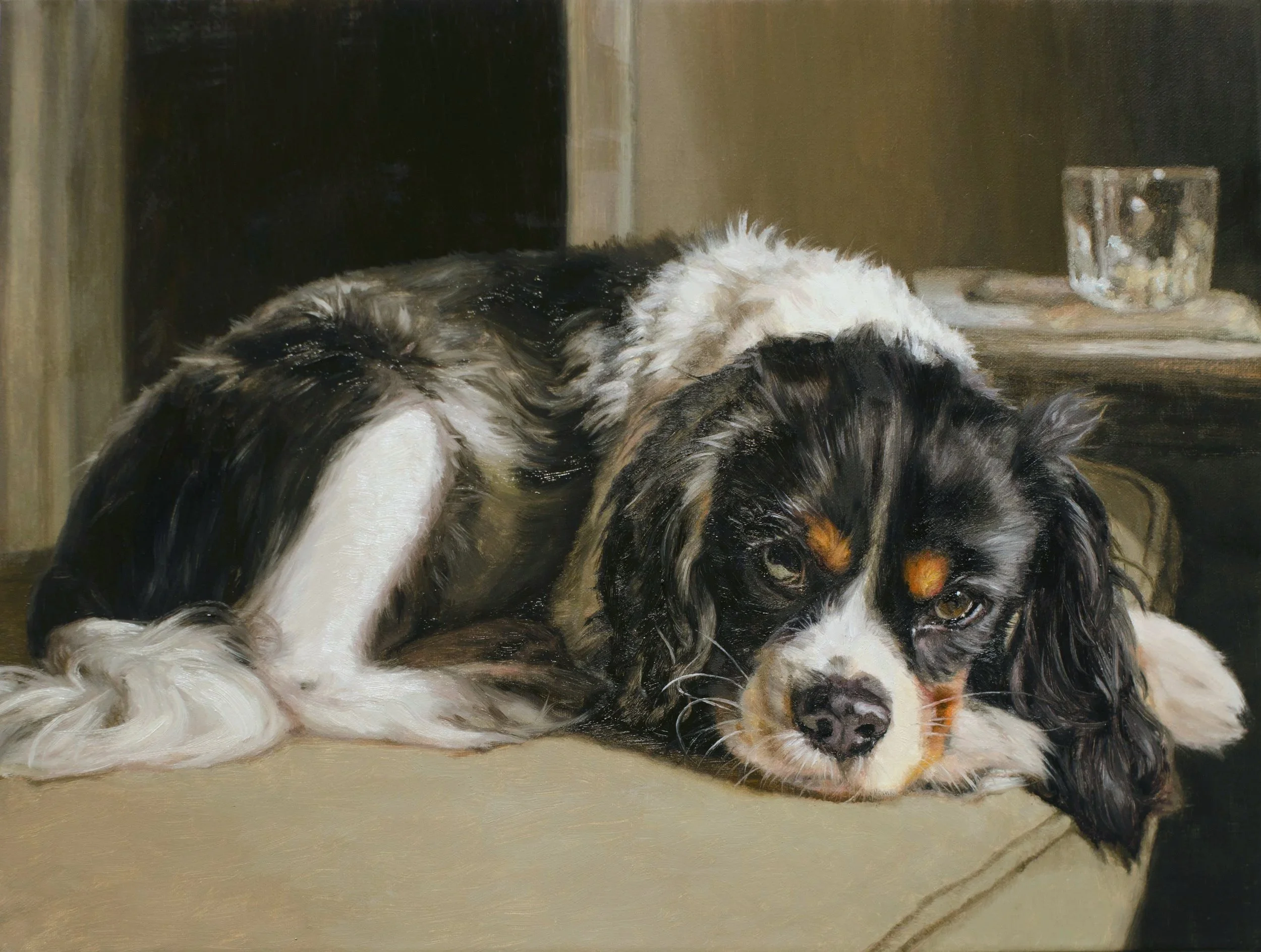 An oil painted custom portrait of a black-and-white Cavalier King Charles Spaniel resting on a couch cushion. Exquisitely detailed.