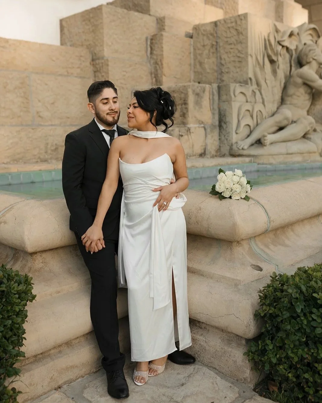 bride and groom holding hands very closely in front of santa barbara courthouse's fountain