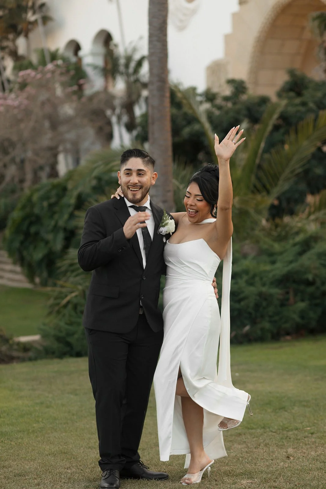 Candid celebratory moment of bride throwing her hand up after being announced married during elopement ceremony at the Santa Barbara Courthouse Sunken Gardens