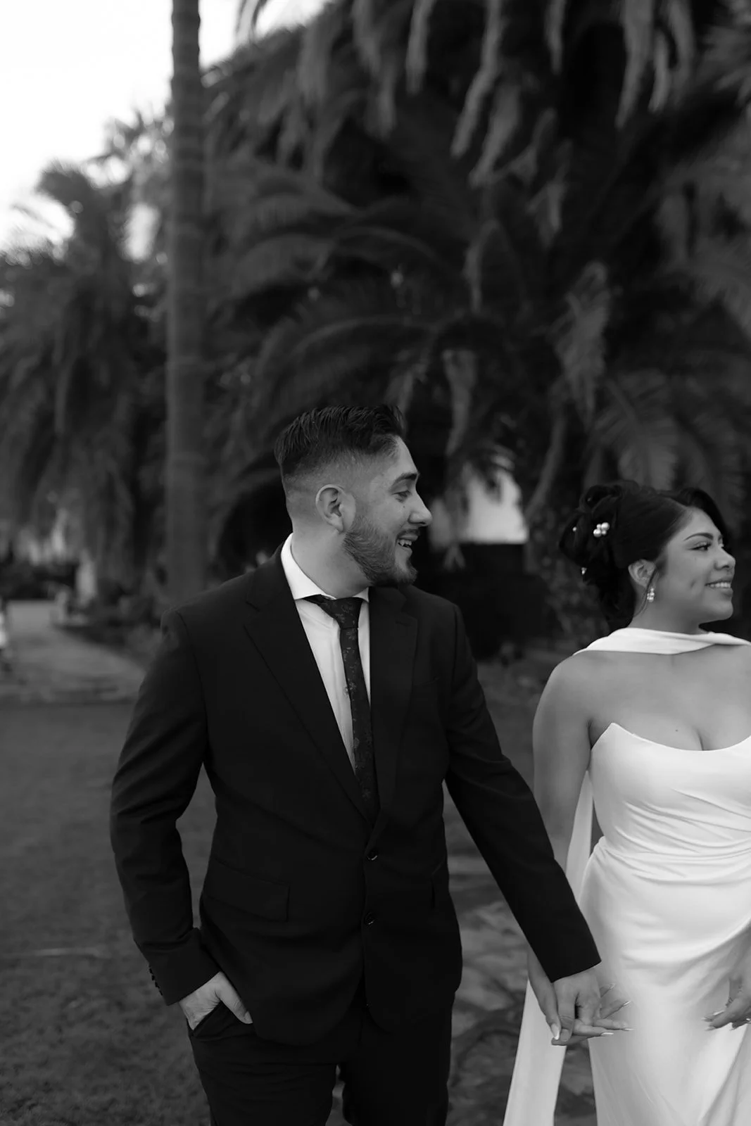 Artsy black and white close-up of couple walking away together at the Santa Barbara Courthouse Sunken Gardens, captured from behind as they move forward side by side