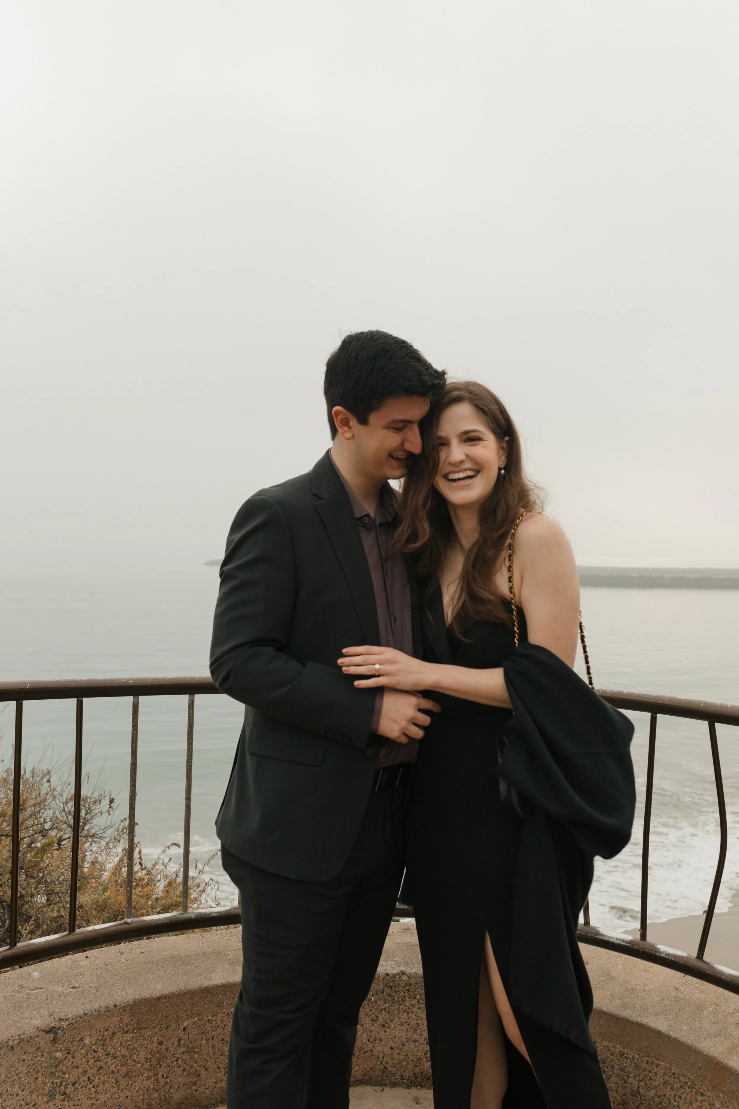 candid photo of couple hugging from proposal at lookout in newport beach with the ocean in background