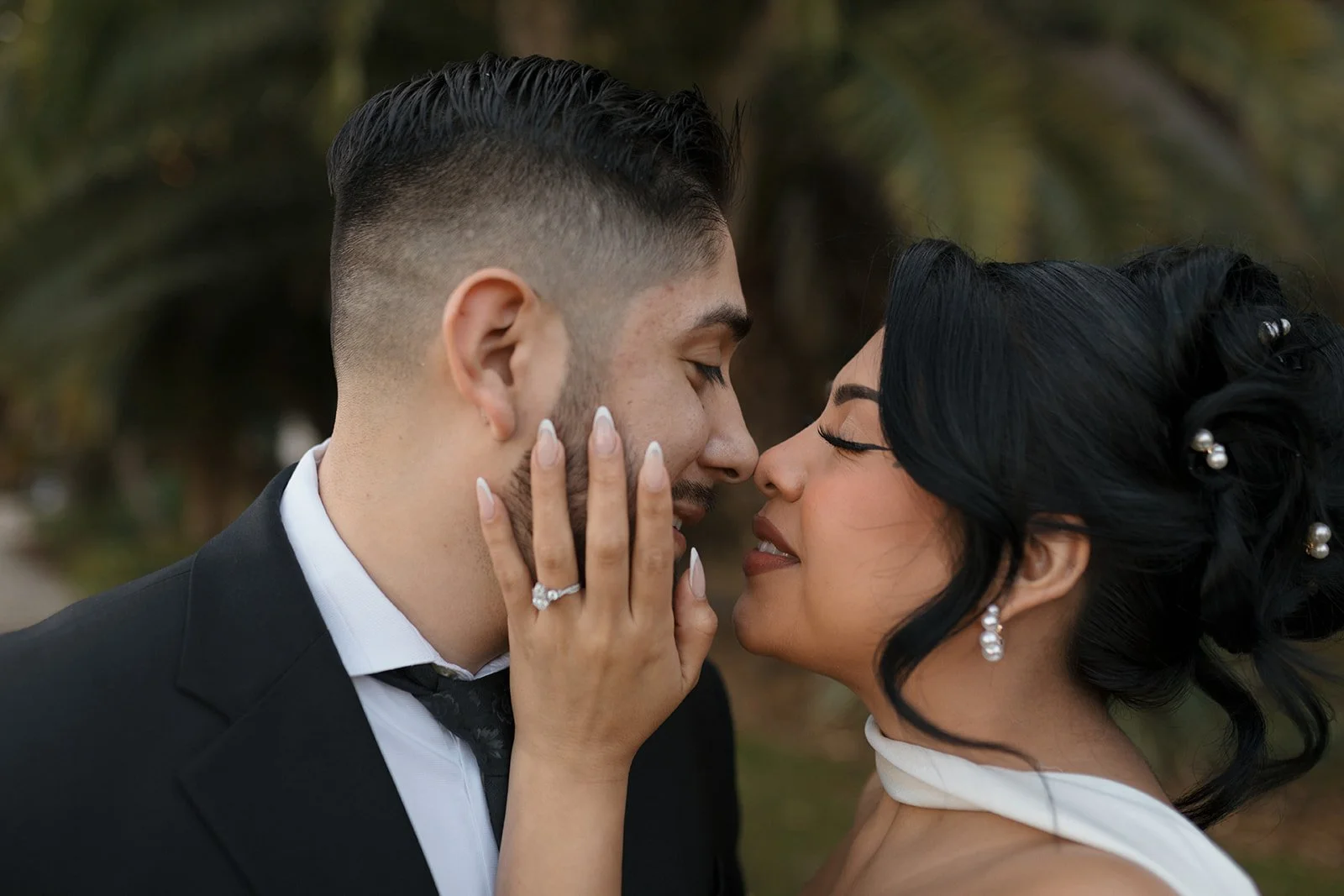Close-up of couple facing each other nose to nose, bride holding groom’s cheek and showing her ring during elopement at the Santa Barbara Courthouse Sunken Gardens