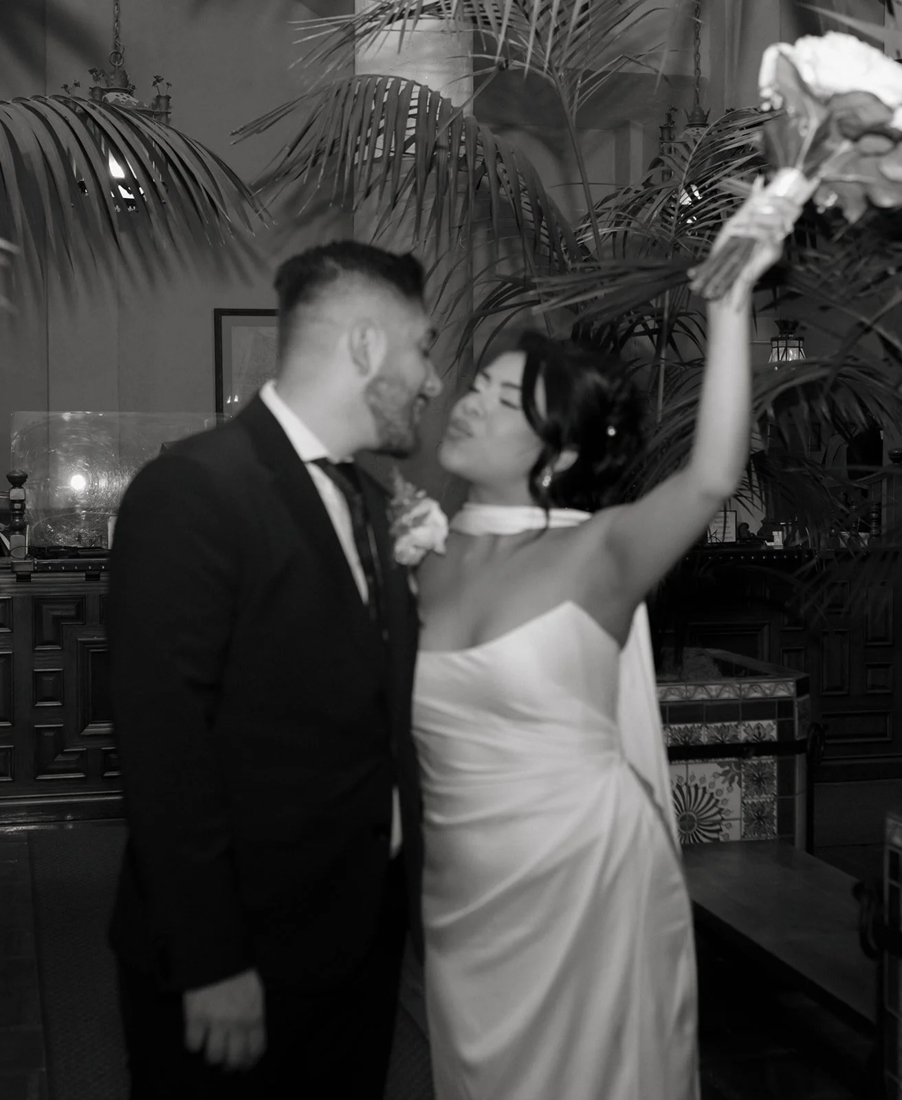 Black and white candid mid-kiss of couple celebrating inside the Hall of Records at the Santa Barbara Courthouse, exiting their elopement ceremony with motion blur, artistic wedding photography