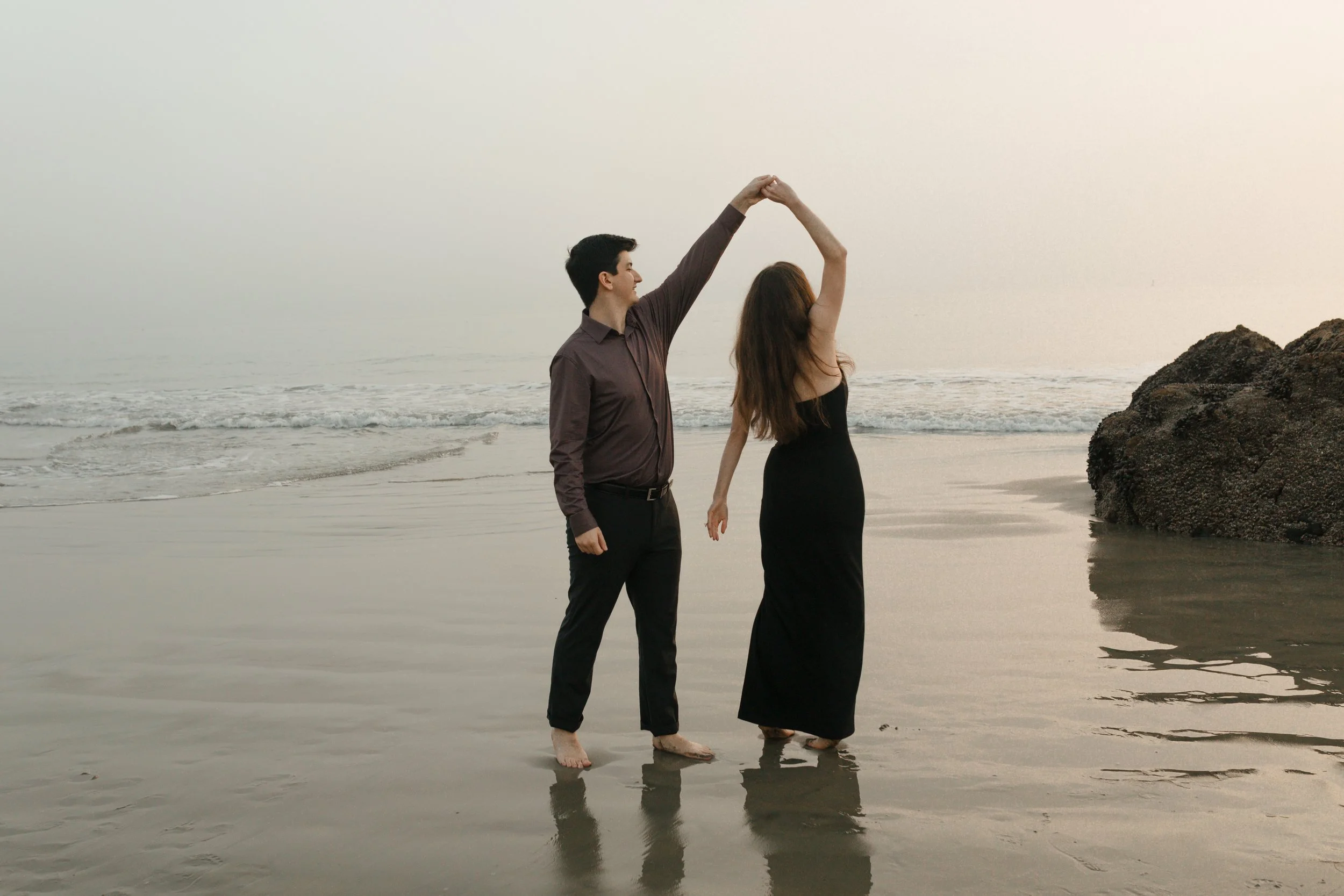 couple danign on the beach from their proposal in Newport Beach. he is spinning her